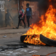 People walk near flaming tyre barricade in Kibera slum in Nairobi, Kenya, August 9, 2017.